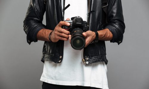 Cropped photo of stylish afro american guy holding digital camera, isolated on gray background